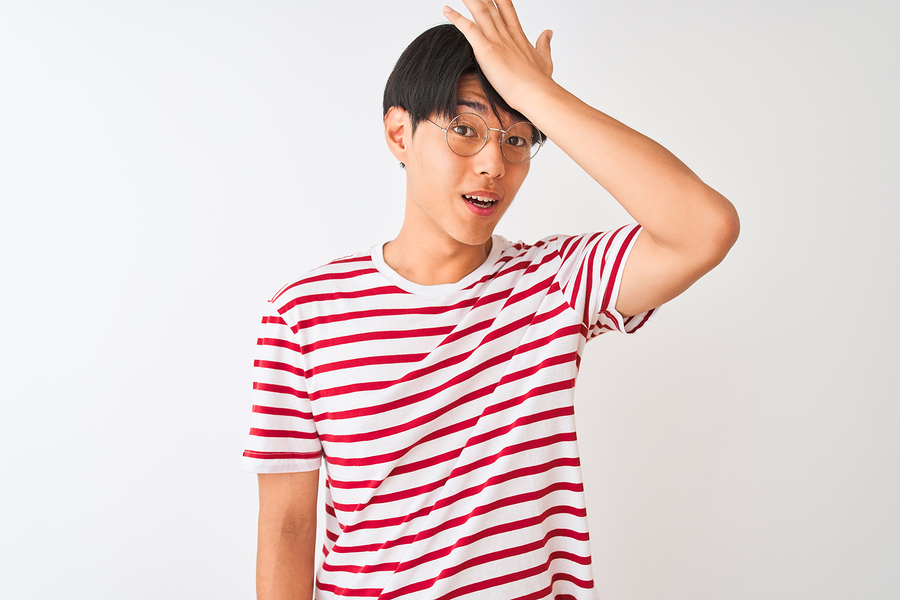 Young chinese man wearing glasses and striped t-shirt standing o