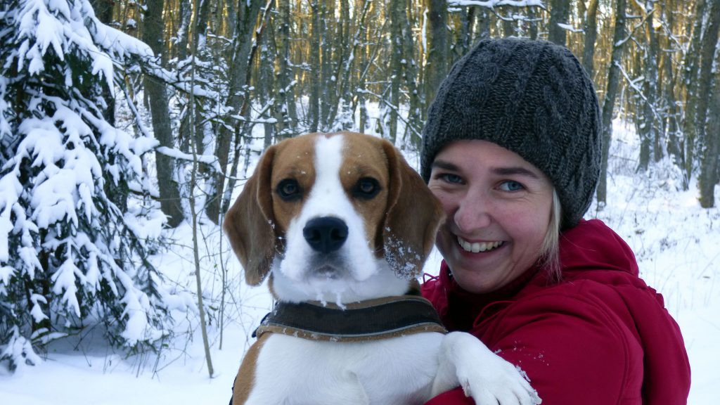 Woman in hat in the snow with her pet dog
