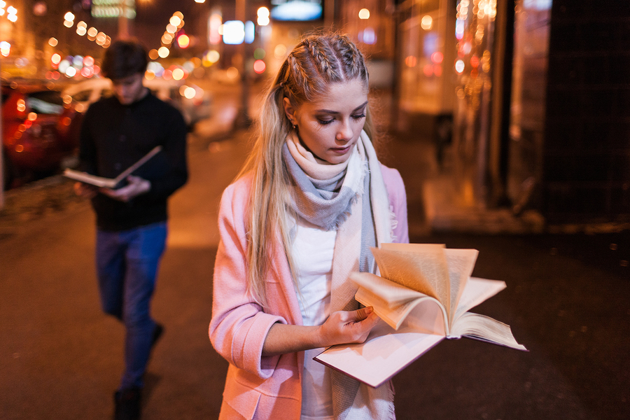 Bookworm on night street. Interesting reading. Student studying outside, search for information in textbook