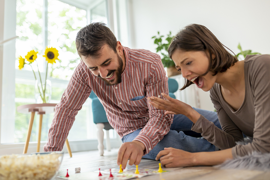 Couple in love enjoying their time together, eating popcorn and having fun while playing ludo board game