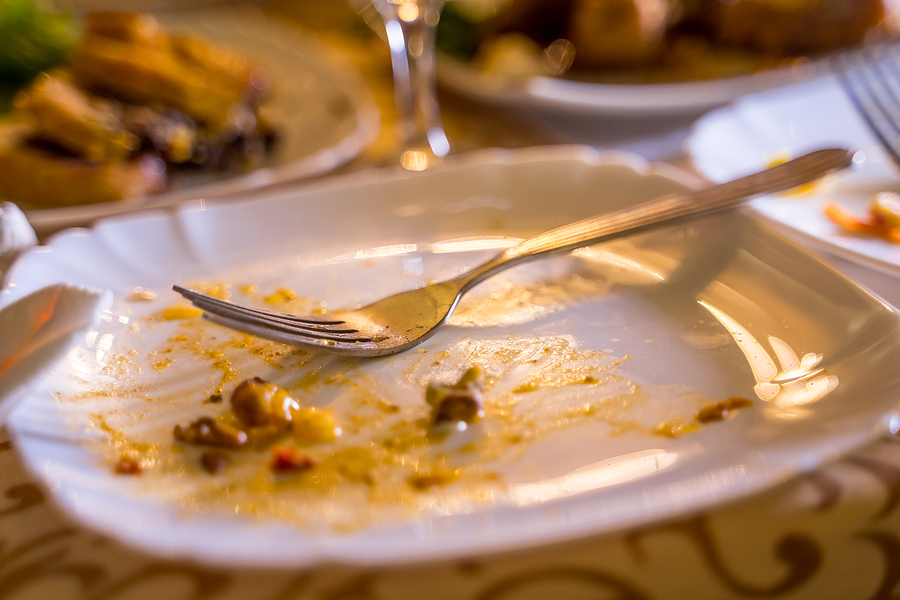 Dirty empty plate with fork on the table. Leavings of food on a plate and a fork after the party in the restaurant. Close up.