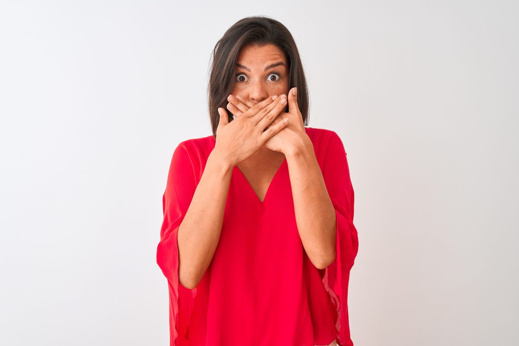 Young beautiful woman wearing red t-shirt standing over isolated white background shocked covering mouth with hands for mistake. Secret concept.